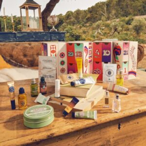 Coffret beauté rose et rouge sur table bois dans nature calendrier de l'avent l'occitane version luxe premium avec 24 produits soins visage corps et cheveux