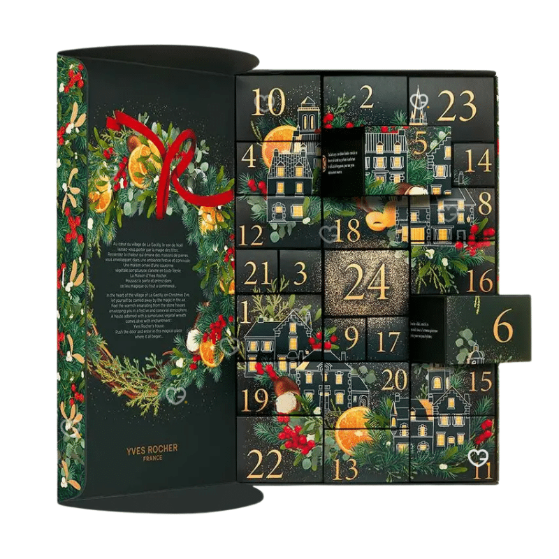Calendrier de l’Avent Yves Rocher 2025 aux couleurs festives verte et décor de village du village de La Gacilly en Bretagne, il renferme 24 produits de beaute : soins visage, corps, maquillage et capillaires dont 6 full-size.