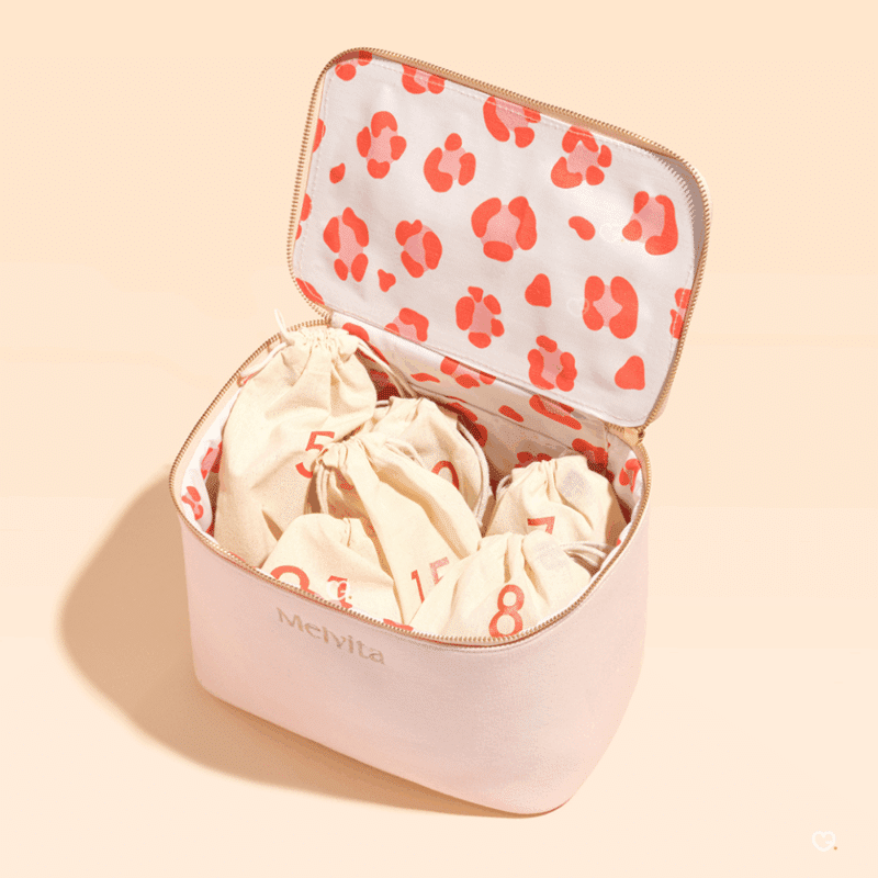 Calendrier de l’Avent Melvita 2025 contenant 24 soins bio visage, corps et cheveux dans une trousse rose écoresponsable pour femmes adeptes de beauté naturelle.