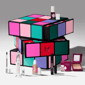Calendrier de l’Avent Benefit 2025 The Glam Cube avec 24 surprises beauté et maquillage, incluant mascaras, blush et soins sourcils.