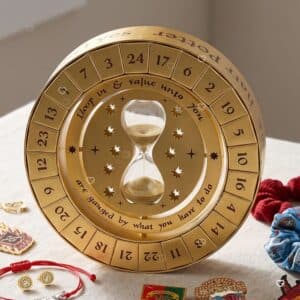 Calendrier de l'Avent Harry Potter Time Turner 2026 posé sur une table entouré de ses 24 bijoux et accessoires The Carat Shop