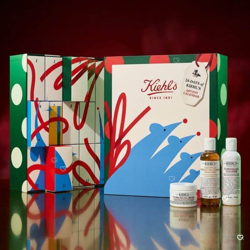 Cases ouvertes du calendrier de l'Avent Kiehl's 2026 sur fond rouge, coffret beauté festif.