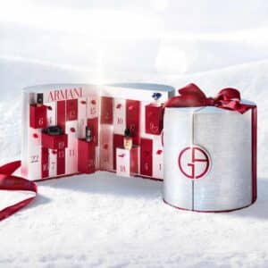 Calendrier de l Avent Armani Beauty 2026 ouvert dans un décor de neige, coffret panettone argenté et rouge
