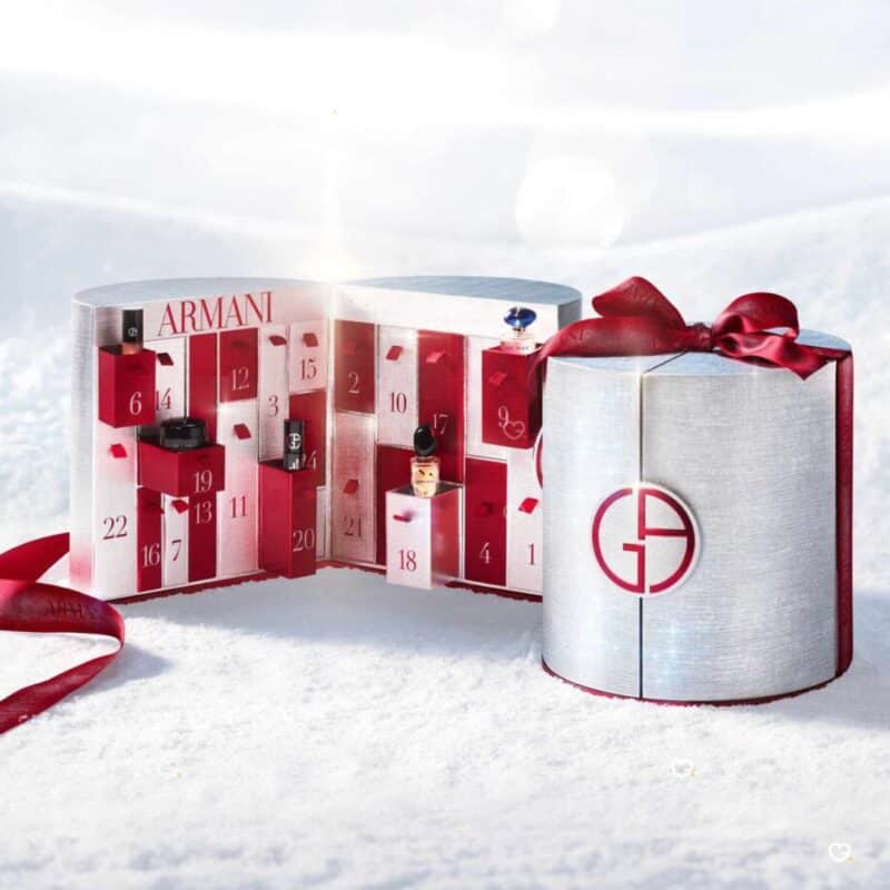 Calendrier de l Avent Armani Beauty 2026 ouvert dans un décor de neige, coffret panettone argenté et rouge